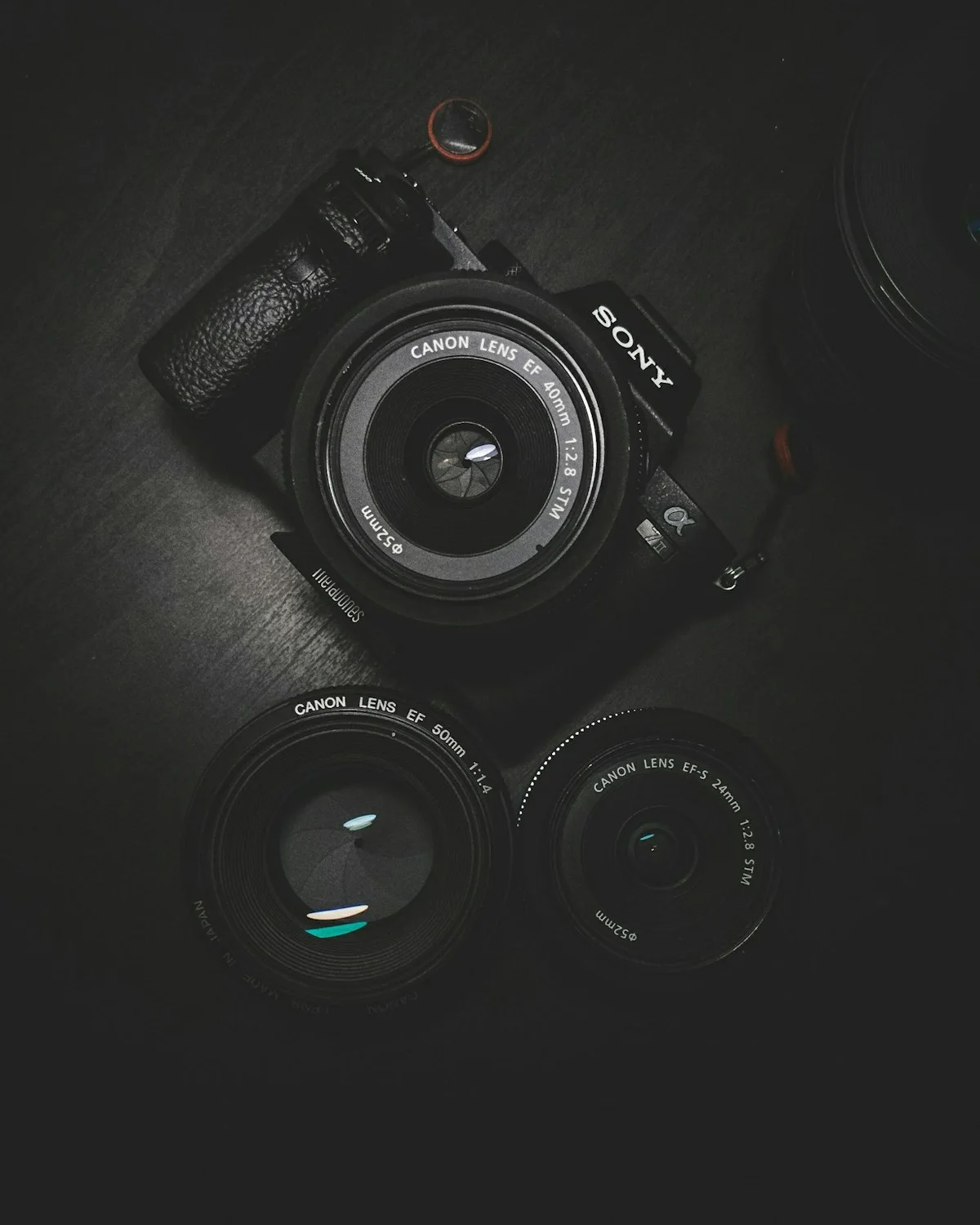 Black camera and interchangeable lenses on a dark surface