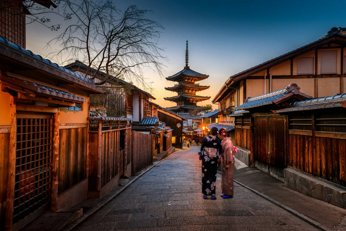 People walking along a traditional street toward a pagoda in Kyoto